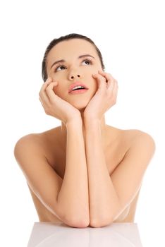 Portrait of a beautiful female model with clean healthy skin looking up, isolated on white background