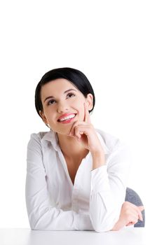Young beautiful happy businesswoman behind the desk looking up on copy space, isolated