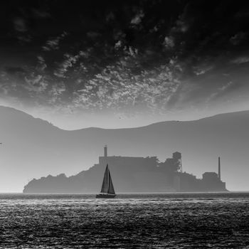 Alcatraz island penitentiary at sunset backlight sailboat in san Francisco California USA