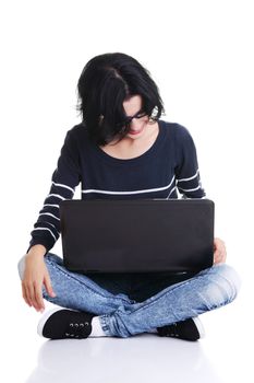 A young thoughtful woman with a laptop sitting isolated on white background