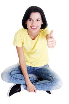 Young woman sitting on floor and gesturing OK , isolated on white