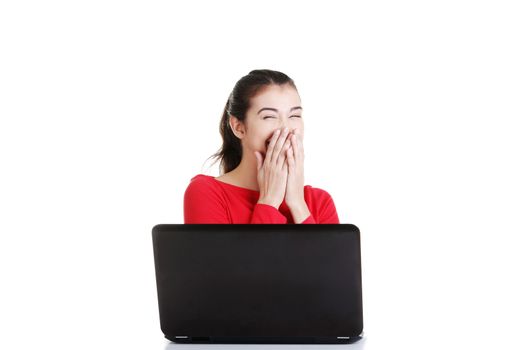 Happy young woman using her laptop at the desk, isolated on white.