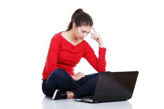 Young pretty woman sitting and working on laptop computer, isolated on white