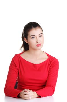 Pretty, happy, young woman in casual clothes sitting at the desk, isolated on white