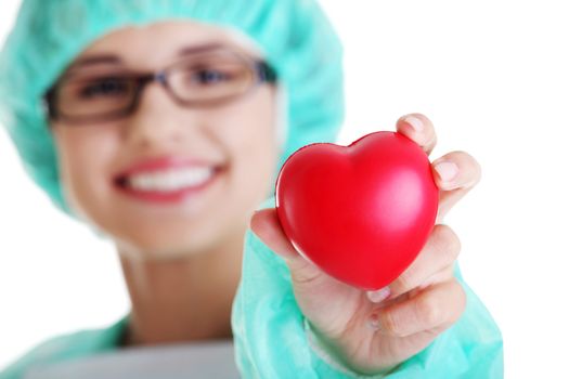 Smiling female doctor or nurse in surgical clothes holding red heart