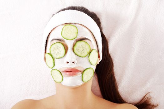 Young woman with cucumber slices on the face in a spa saloon