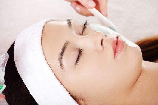 Beauty treatment in spa salon. Woman with facial clay mask.