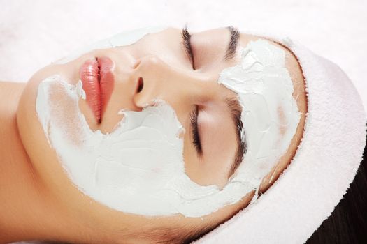 Beauty treatment in spa salon. Woman with facial clay mask.