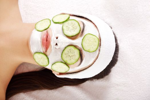 Young woman with cucumber slices on the face in a spa saloon