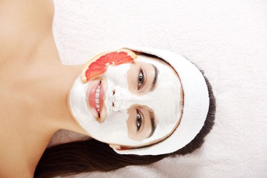 Attractive young woman with fruit mask on a face at spa saloon