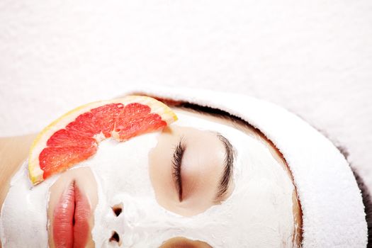 Attractive young woman with fruit mask on a face at spa saloon