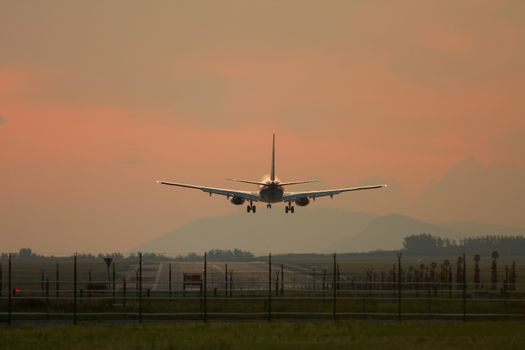 Airliner landing against sunset sky