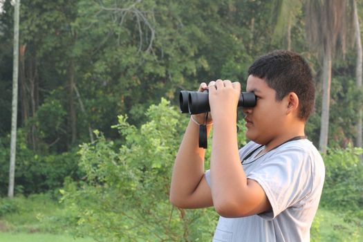 Thai boy looking the nature through binoculars