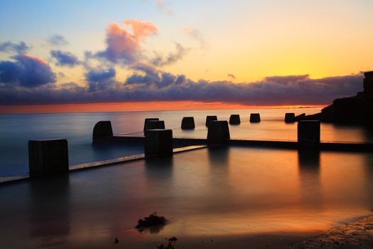 Spectacular sunrise at the Coogee Baths, south side, Coogee, Australia.  The sun lit up the summer sky.  Long exposure.