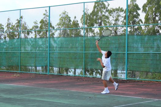 Thai young tennis player serving the ball