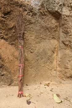 Whisk broom leaning against stone wall on hill