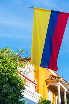 View of the Colombian flag with colonial architecture and blue sky in Cartagena, Colombia