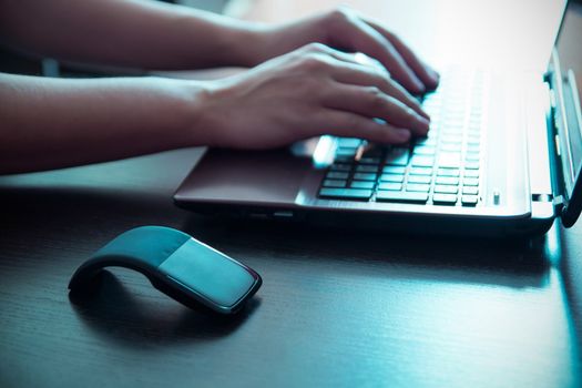 Human hand on computer mouse. Laptop on desk.