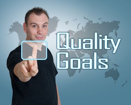 Young man press digital Quality Goals button on interface in front of him