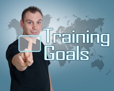 Young man press digital Training Goals button on interface in front of him
