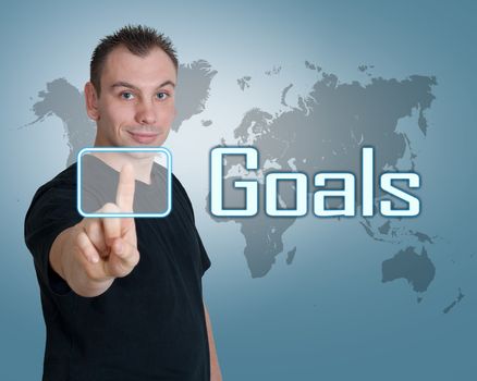 Young man press digital Goals button on interface in front of him