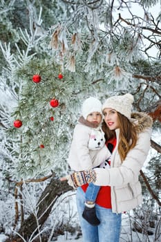 Mother holds daughter in her arms in the winter forest