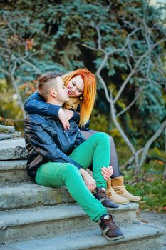 Attractive young couple sitting on the steps and hugging each other