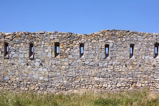 Ancient broken wall with little windows among the field