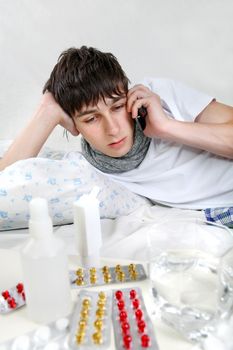 Sick Young Man talking on Cellphone on the Bed
