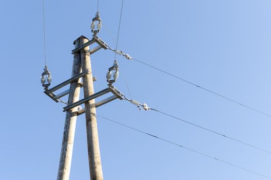 Powerlines on wooden pillar with blue sky in background.