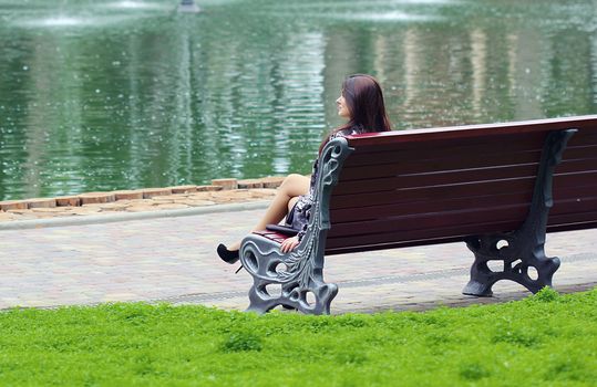 Woman sitting near the river at the bench