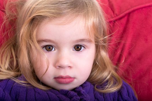 Close up facial portrait of a beautiful innocent young blond girl with a solemn wide eyed expression staring into the camera