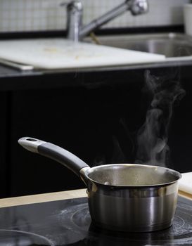 Little saucepan with boiling water on the plate