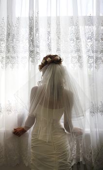 The beautiful bride prepares for wedding. Silhouette on a background of a window
