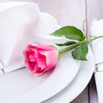 Romantic formal elegant table setting with a single pink rose and decorative ribbon for a sweetheart on Valentines Day