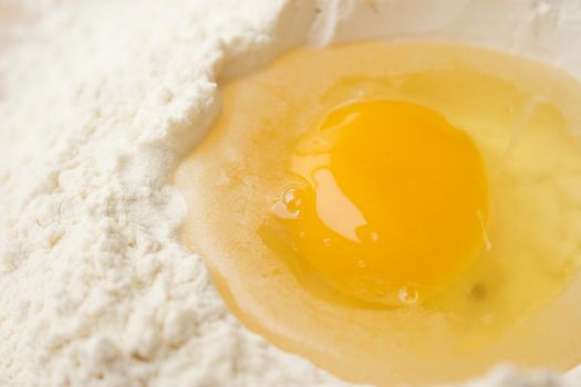 Flour on a wooden cutting board with a egg in the middle of it.