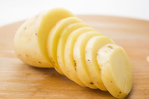 Sliced potato on a wooden cutting board.