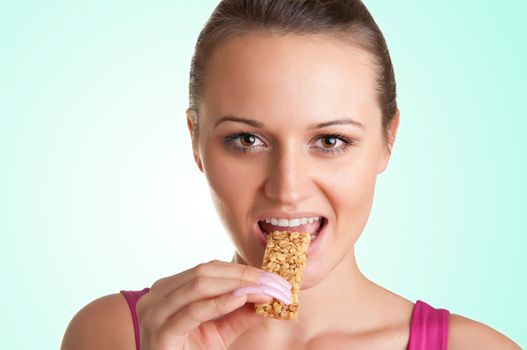 Sexy young woman eating a cereal bar, in a green background