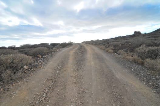 Sand and Rocks Road in the Desert on a Cloudy Sky