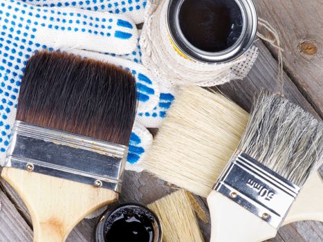 Arrangement of Black and Grey Oil Colors, Various Paint Brushes and Protective Gloves closeup on Wooden background. Top View