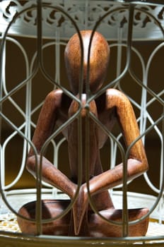 Wooden figurine in a cage