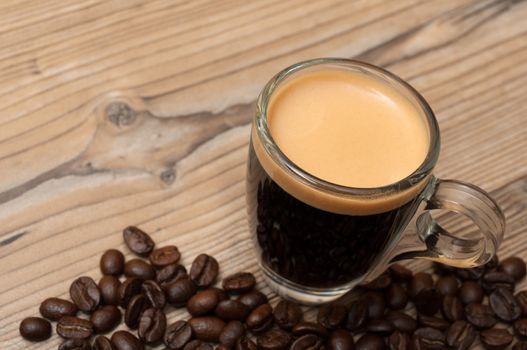 Glass Cup of Espresso Coffee on Wooden Table With Coffee Beans - Shallow Depth of Field