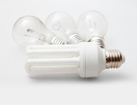 New Energy Saving Bulb and Three Aged Burnt Tungsten Bulbs on Light Background