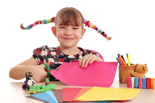 happy little girl cutting paper with scissors