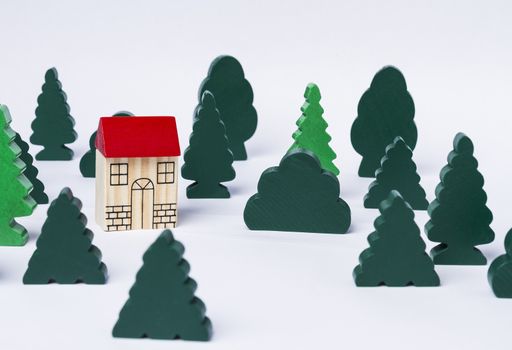 simple toy house in forest made of several trees. Grey background