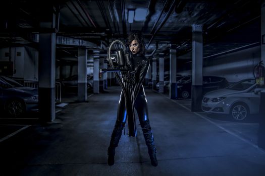 armed woman in a garage, future concept, black latex with neon lights