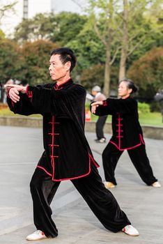 Shanghai, China - April 7, 2013: people exercising tai chi with traditional costume in gucheng park in the city of Shanghai in China on april 7th, 2013