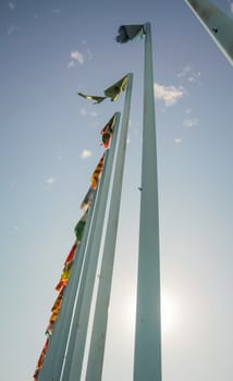Bottom view of flag masts group over blue sky background