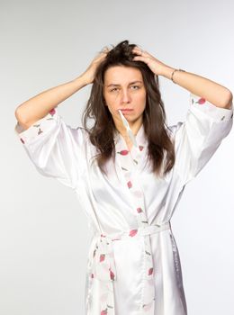 Woman in peignoir with toothbrush on grey background