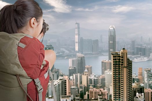 Young backpacker travel and take picture at Hong Kong with famous skyscrapers in daytime.